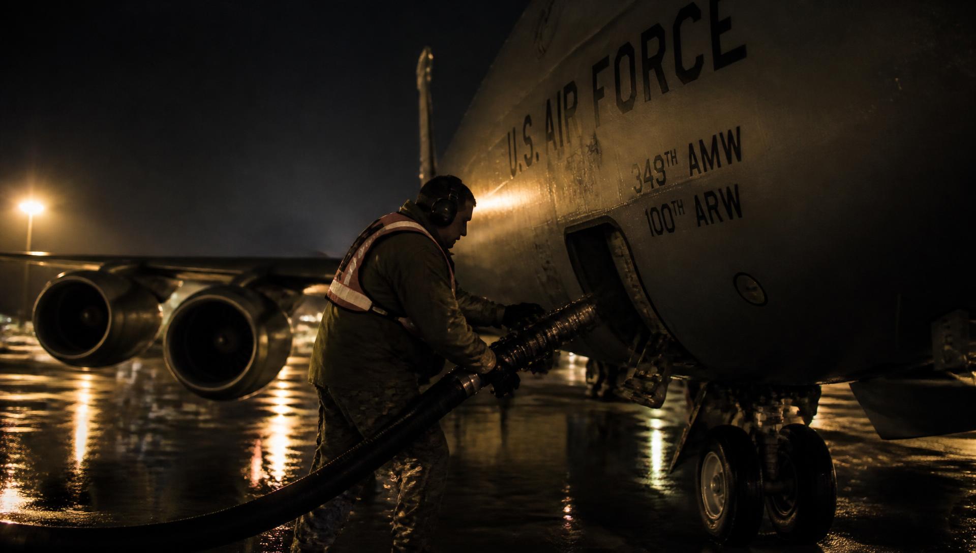 Air Force fuels Airman refueling a KC-135 tanker on a wet flightline at night